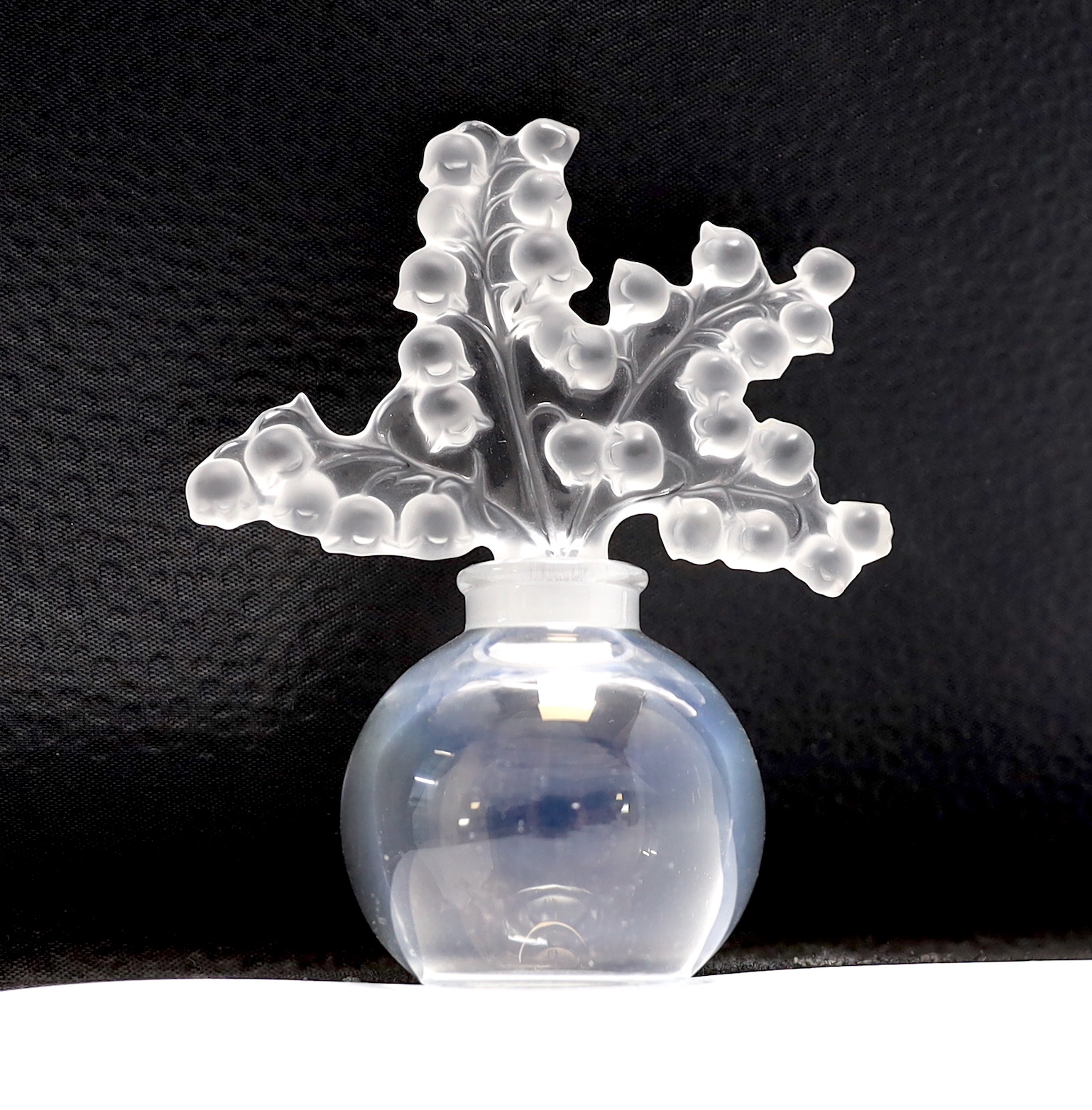 Three Lalique glass scent bottles and stoppers, one with Lily of the Valley stopper, 12cm